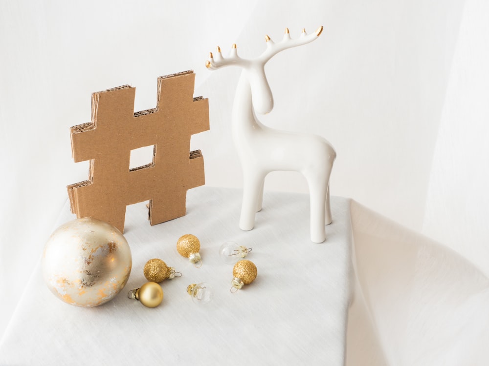 a white reindeer figurine next to a cardboard hash sign