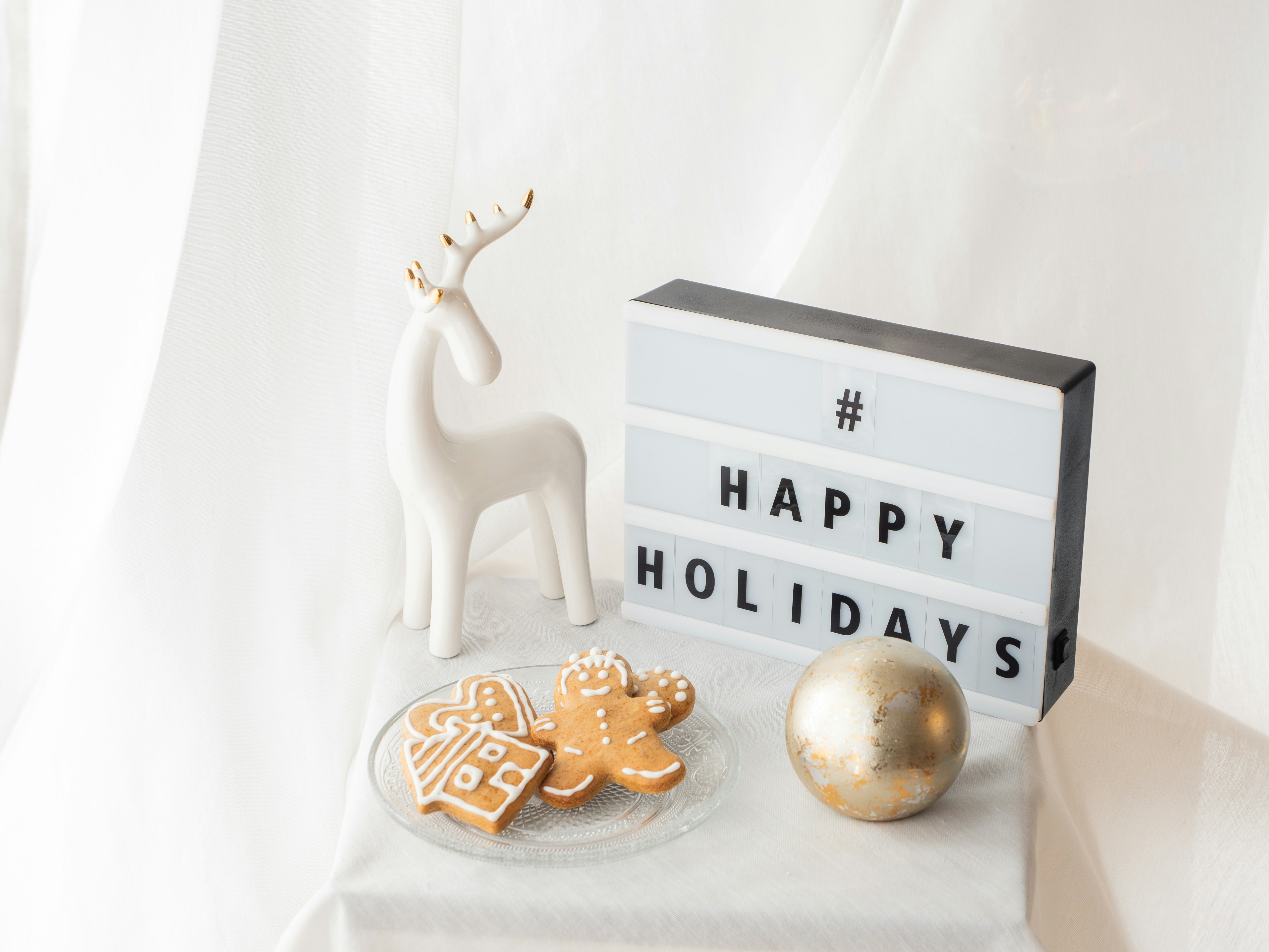 ハッピーホリデーの看板の隣にある白いトナカイの置物