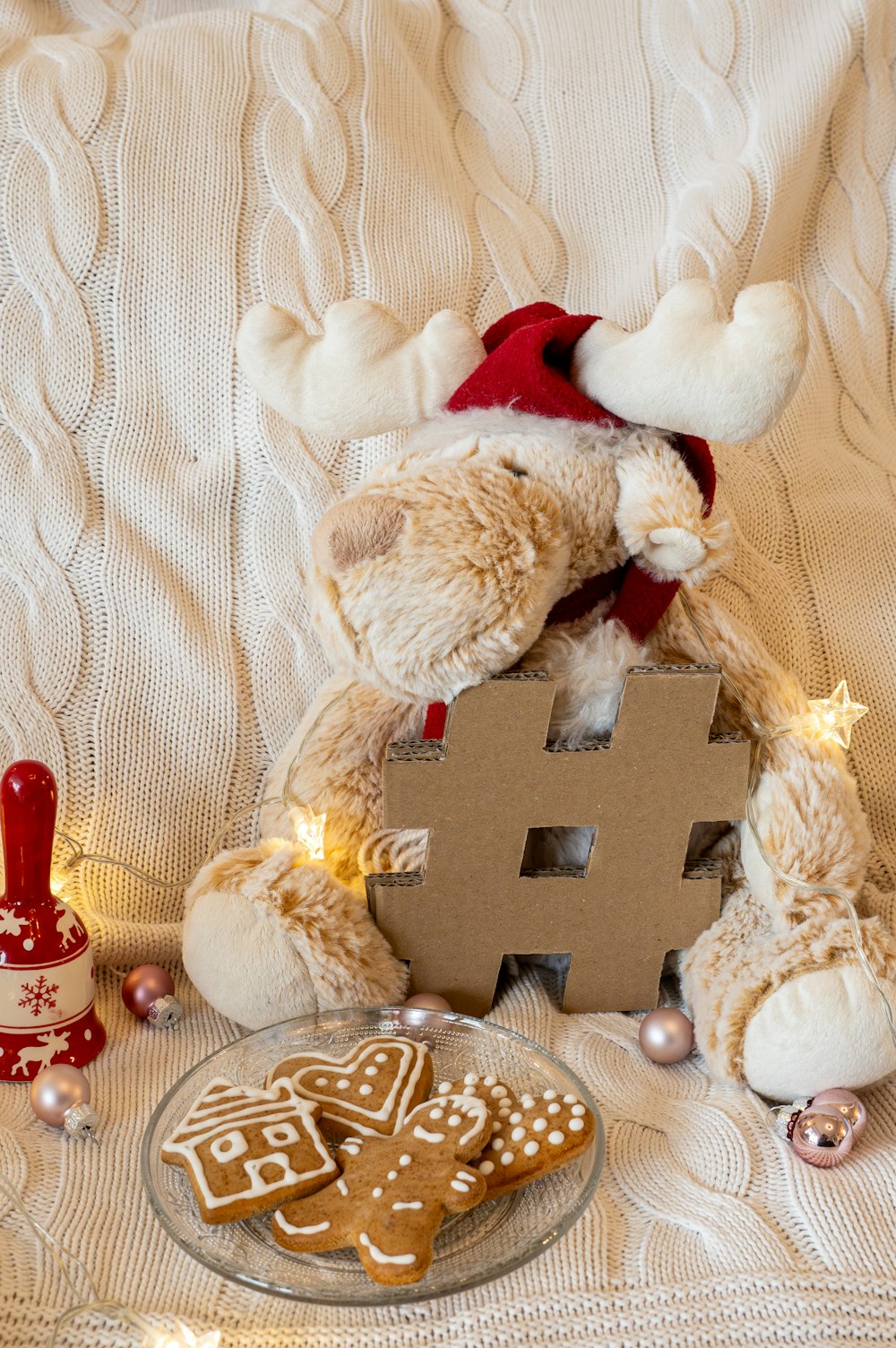 a teddy bear sitting on a bed next to a plate of cookies