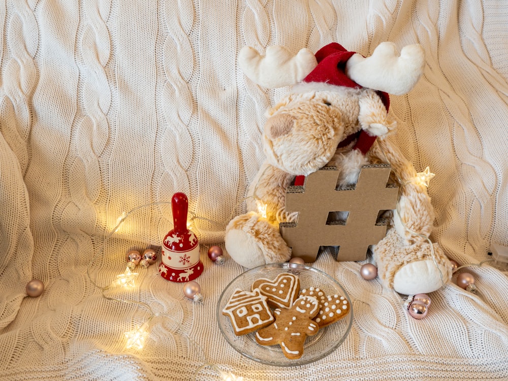 a teddy bear sitting on a bed next to a plate of cookies