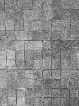 A pattern of small, square tiles with a textured, stone-like appearance, arranged in a grid pattern.
