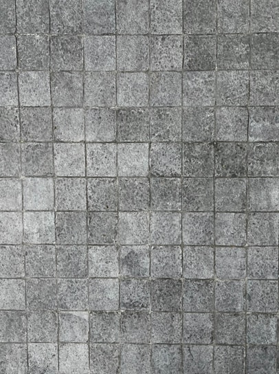 A pattern of small, square tiles with a textured, stone-like appearance, arranged in a grid pattern.