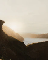 A golden sunrise over the Needles cliffs, casting warm light on the sea.
