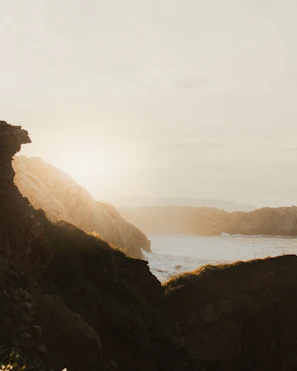 A golden sunrise over the Needles cliffs, casting warm light on the sea.