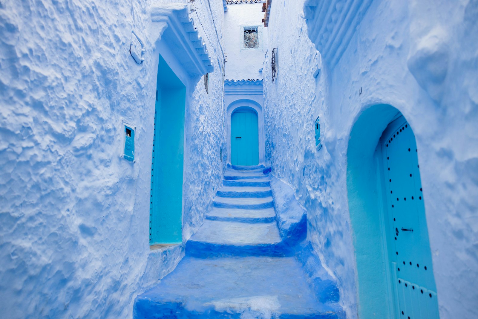 Narrow blue-washed alley and staircase with arched doorways in Chefchaouen