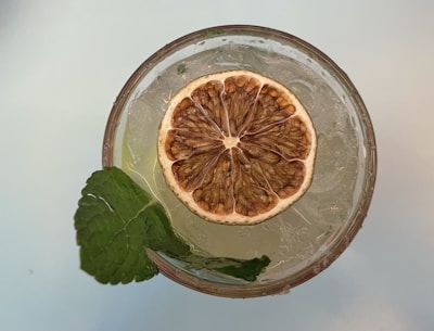 Top-down view of a detox water bottle infused with dried cucumber and mint leaves.