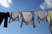 Freshly washed clothes hanging outdoors under natural sunlight.