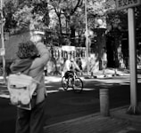An UrbanLens camera hanging from a cyclist’s shoulder as they ride through a bustling urban street.