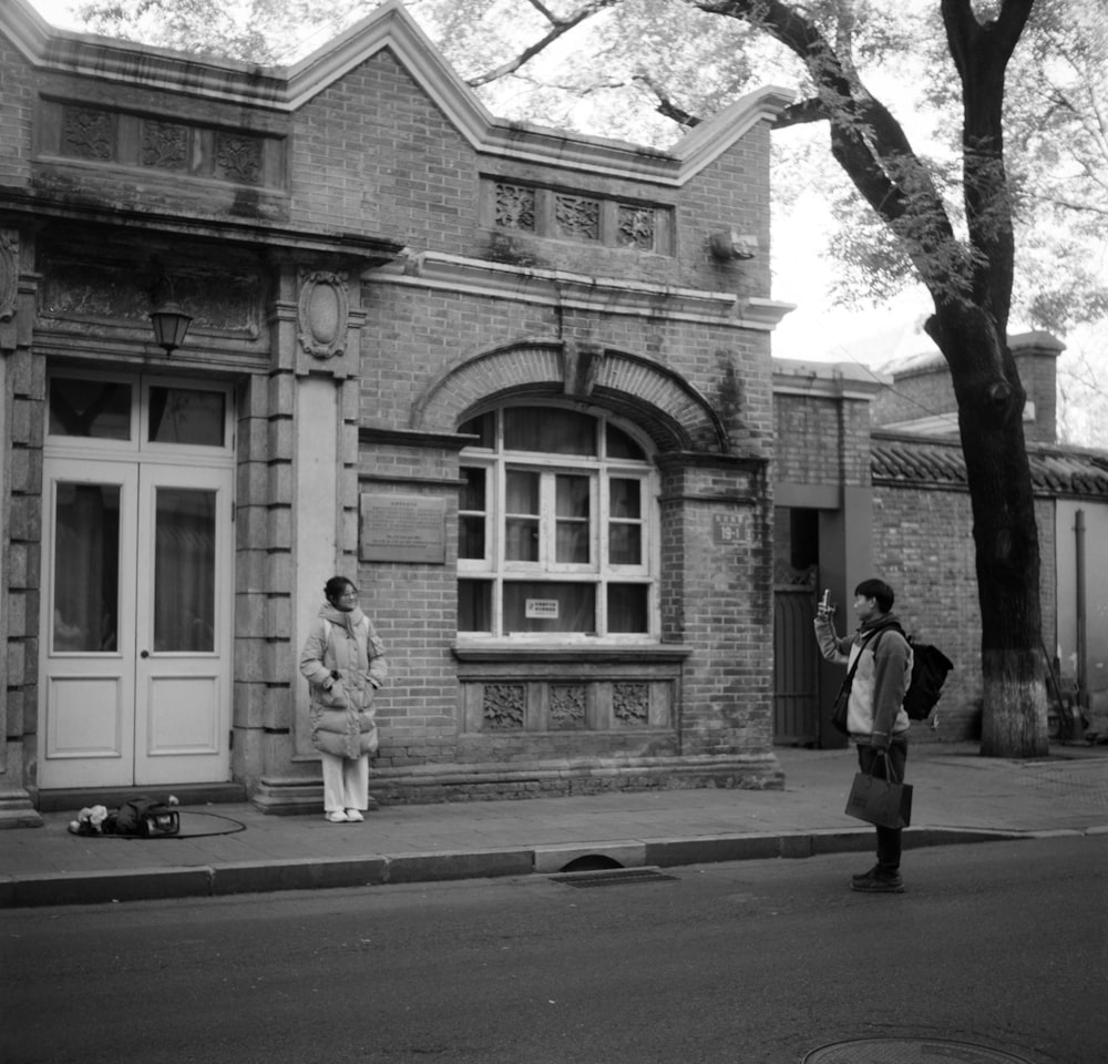 a black and white photo of two people standing in front of a building