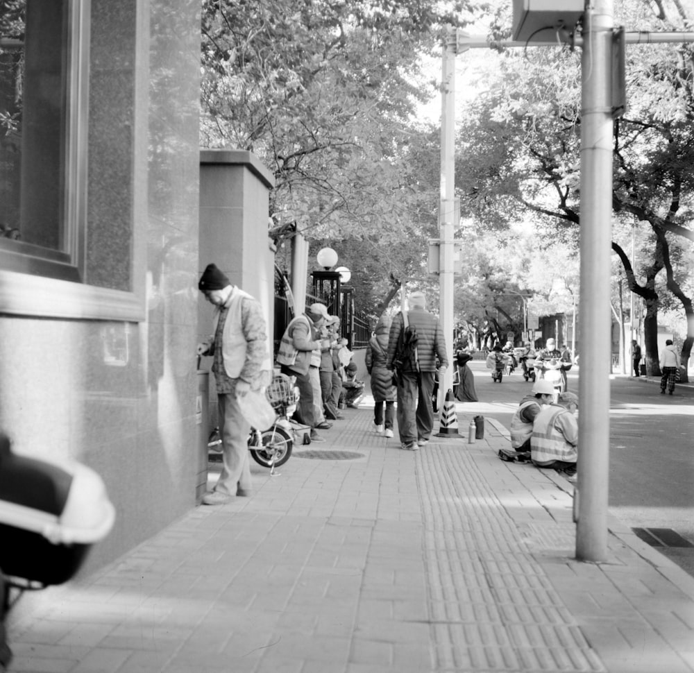 a black and white photo of people walking down a sidewalk