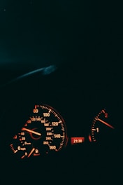 A close-up of a sleek, modern car dashboard clock glowing softly in the evening light.