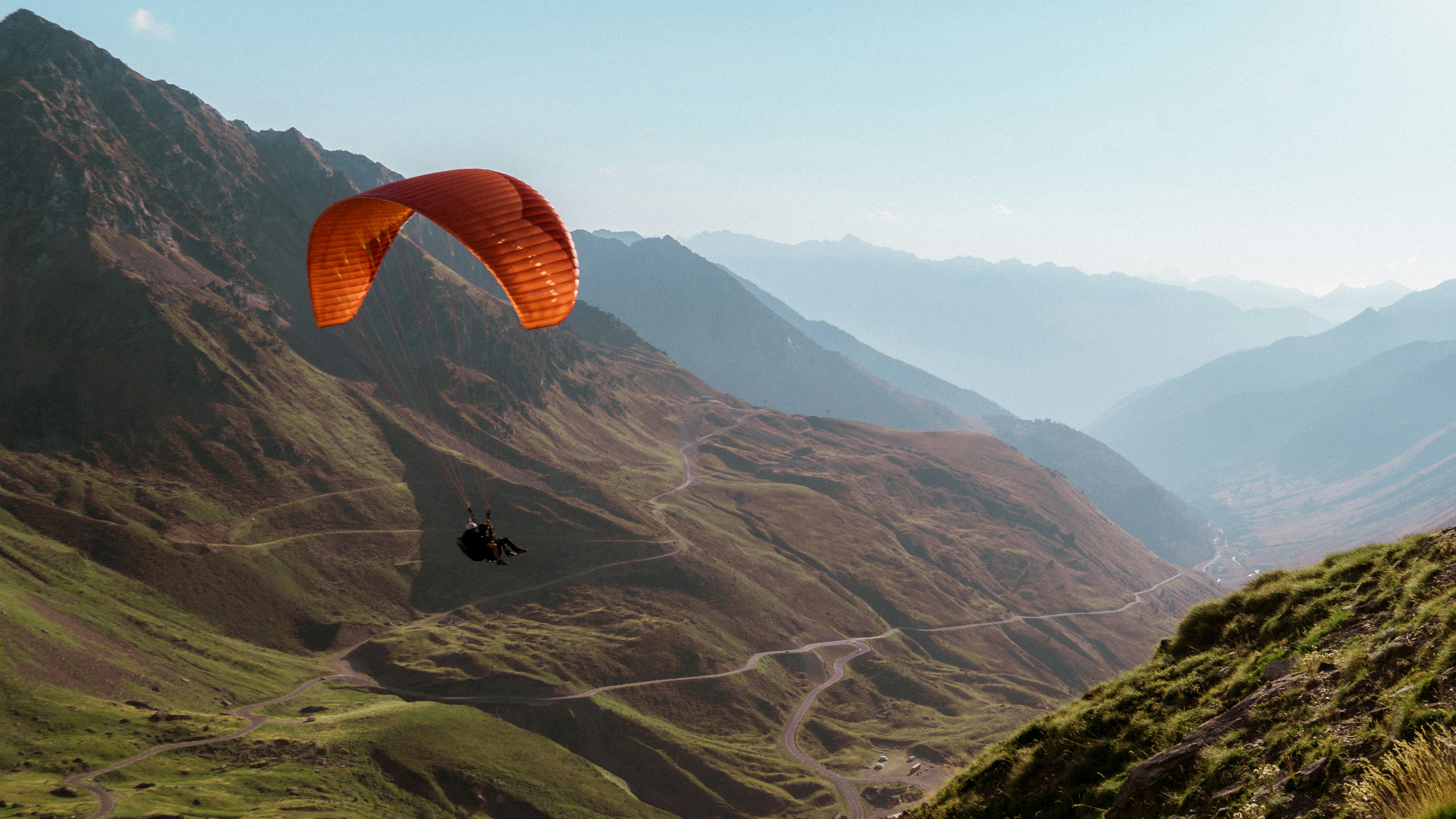 a paraglider is flying over a mountain range
