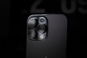 Close-up view of a smartphone's rear camera module featuring multiple lenses, highlighted by a soft, diffused light against a dark background, emphasizing the sleek and modern design.