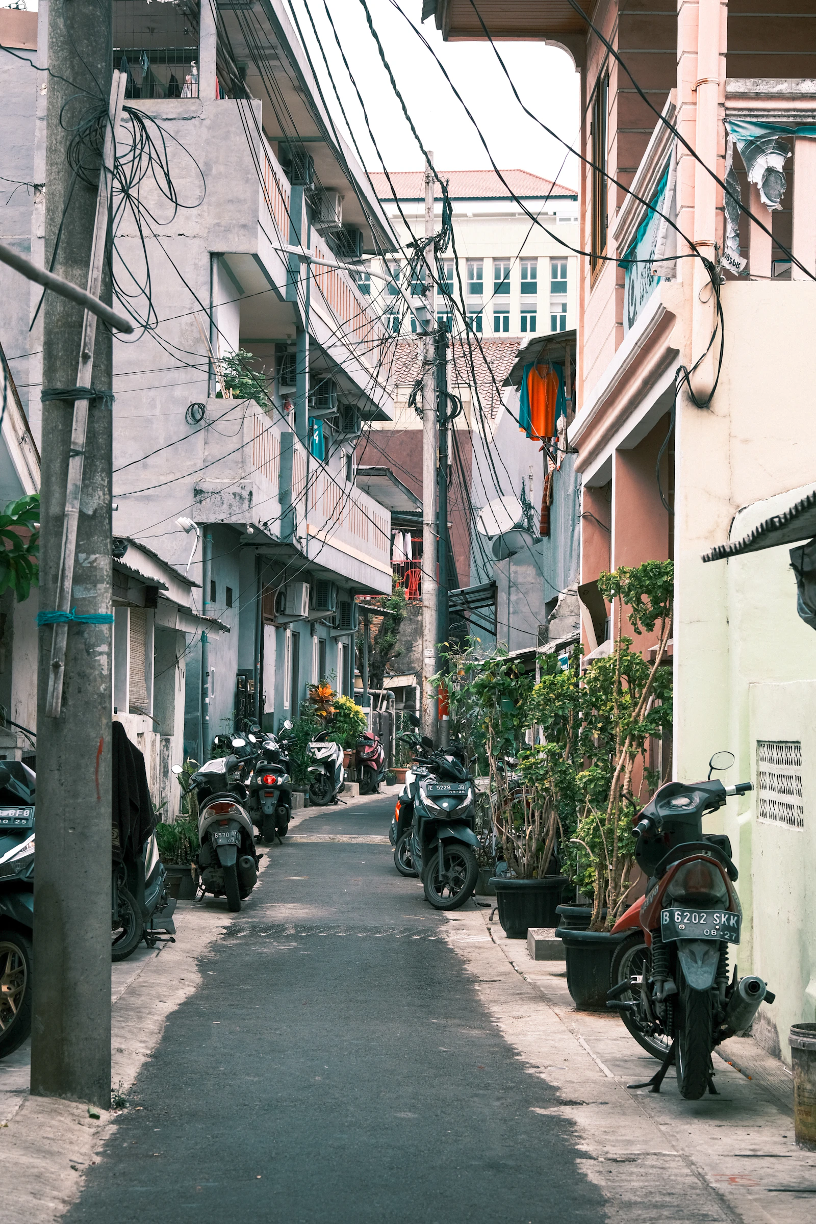 Gang sempit di Jakarta dengan motor parkir di kedua sisi — ilustrasi lingkungan komplek warga DKI yang banyak properti warisan dengan SPPT PBB atas nama almarhum