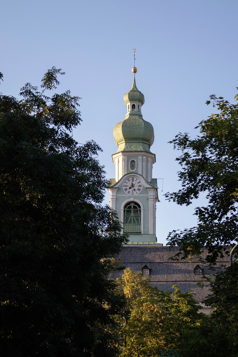 a tall white and green tower with a clock on it's side