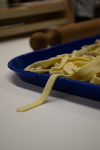 Close-up of hand-rolled fresh pasta strands resting on a wooden board.
