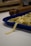 Freshly made pasta is laid out in a blue tray on a white countertop. In the background, there is a wooden rolling pin, slightly out of focus.