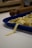 Freshly made pasta is laid out in a blue tray on a white countertop. In the background, there is a wooden rolling pin, slightly out of focus.