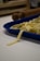Close-up of hands rolling fresh pasta dough on a wooden board in a bright kitchen.