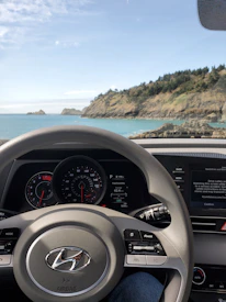 A sleek, modern dashboard view from inside a car driving along a scenic coastal road.