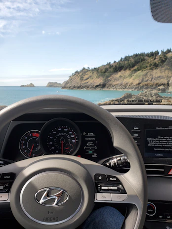 A dashboard view of a car driving along a scenic coastal highway.