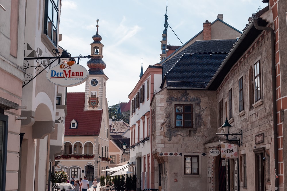 a narrow street with a clock tower in the background