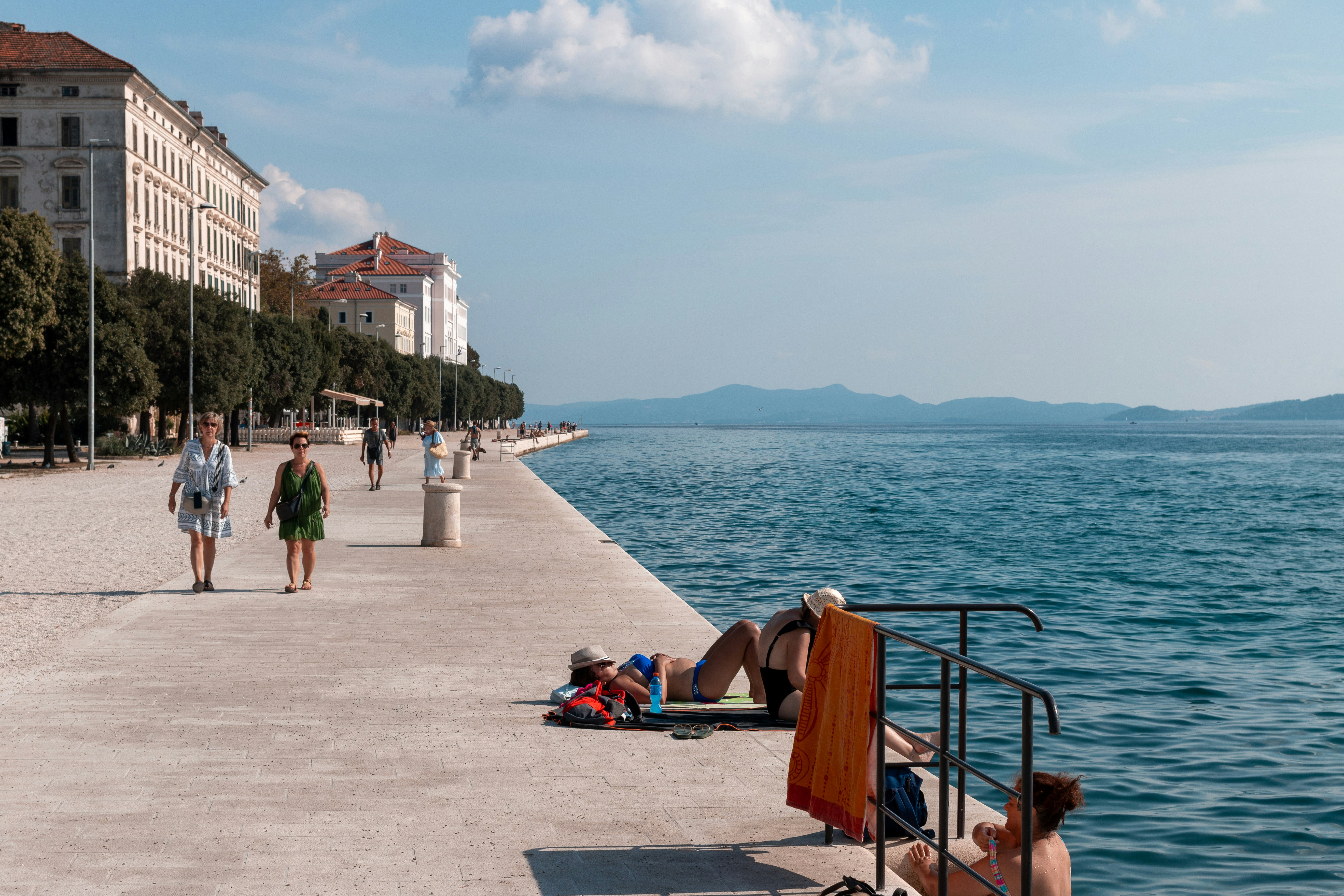 A group of people walking along a beach next to a body of water