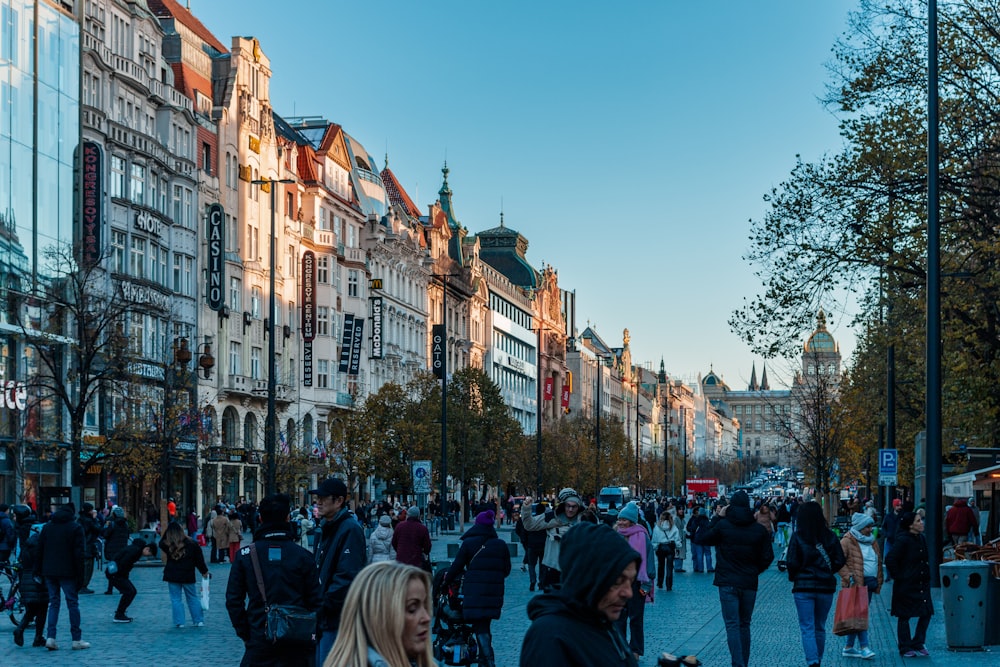 a crowd of people walking down a street next to tall buildings