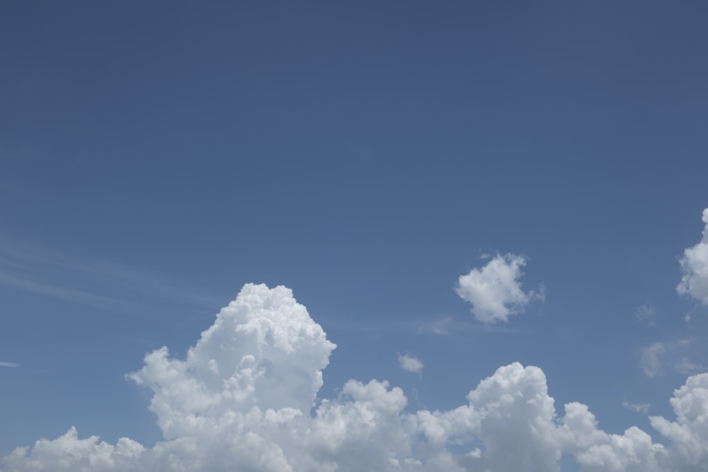 a plane flying high in the sky with clouds