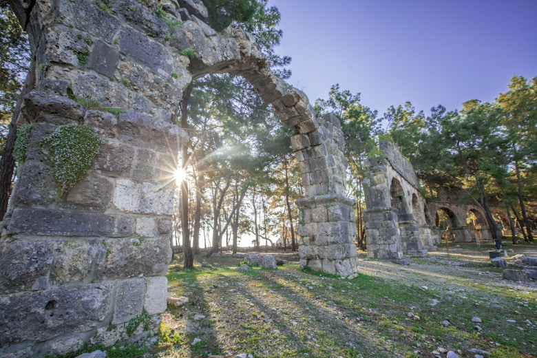 the sun shines through an arch in the ruins of a building