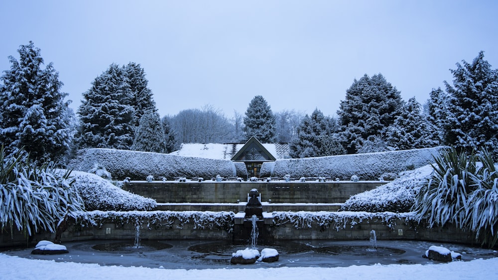 a snow covered garden with a fountain in the middle