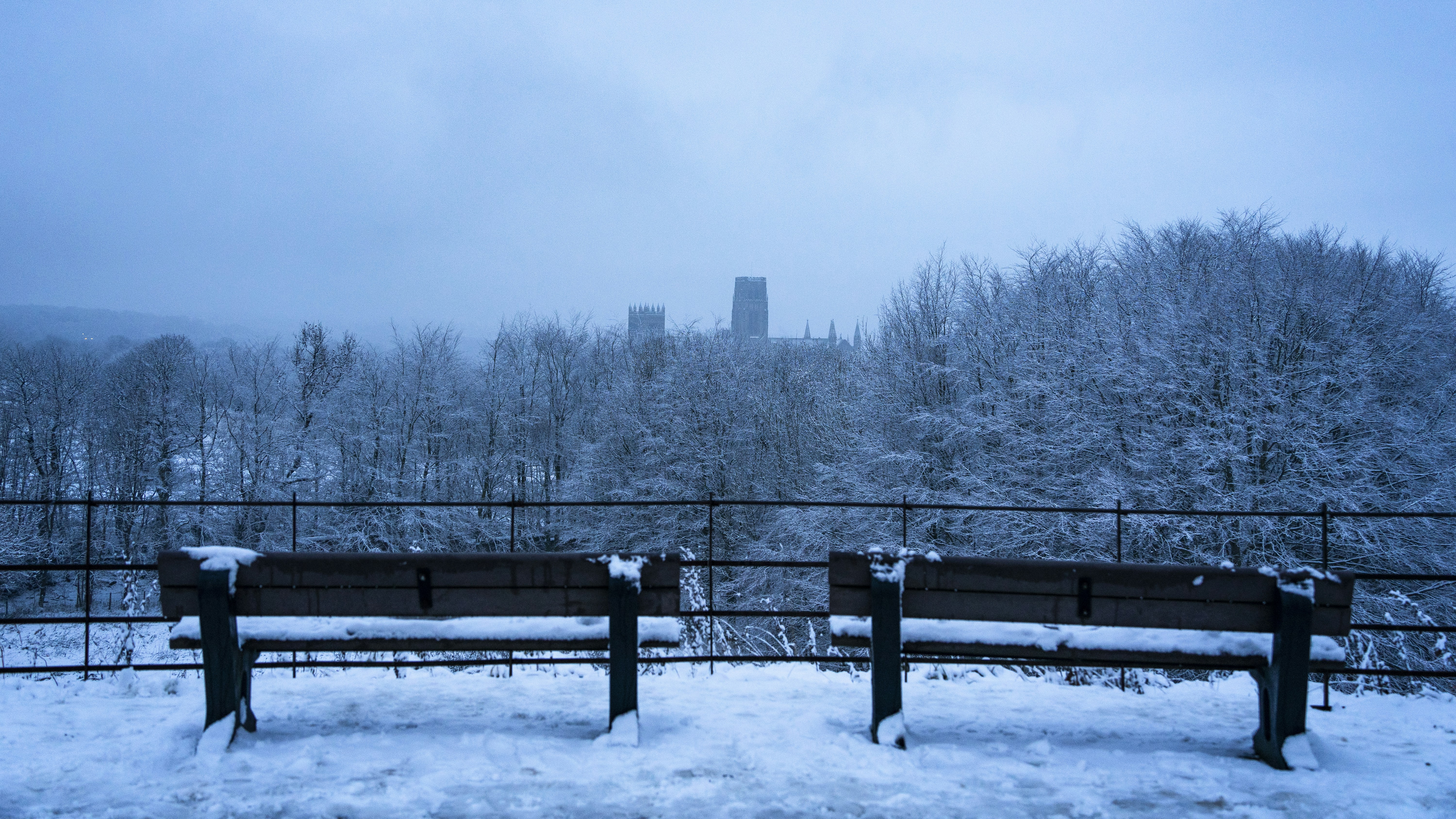 a couple of benches sitting on top of a snow covered field