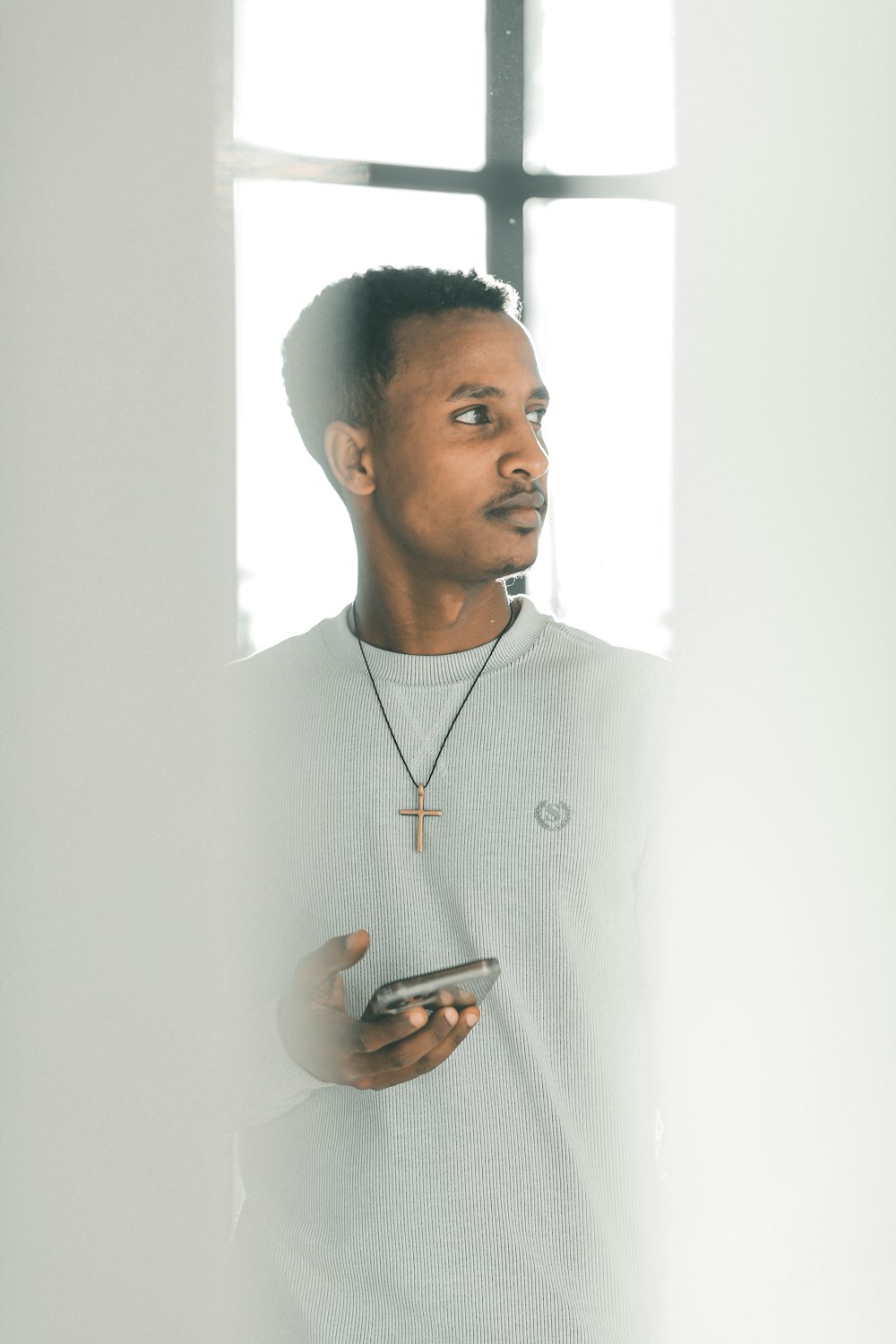 a man standing in front of a window holding a cell phone