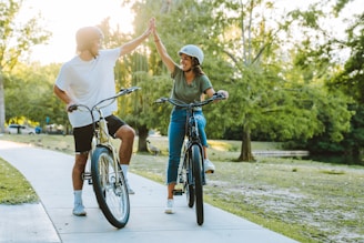 a man and a woman on bicycles giving each other a high five