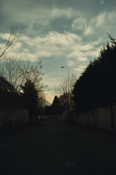 A quiet street bathed in golden late afternoon light, capturing a solitary figure lost in thought.
