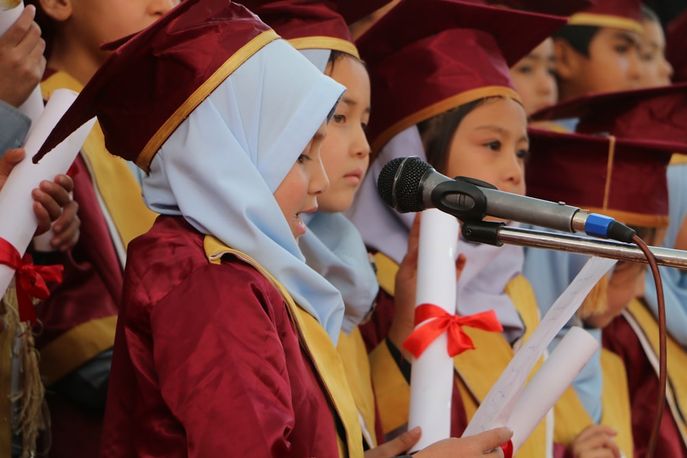 a group of children in graduation gowns holding diplomas