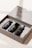 A close-up of an open box containing three small black bottles with labels that read 'travel kit'. The kit appears to be a mockup template or cosmetic set with a clean and minimalist design.