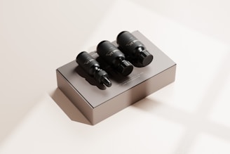 Three black dropper bottles are placed on a matte beige box with subtle shadows. The scene is minimalistic, featuring a neutral background with a soft lighting effect that creates a calm and luxurious appearance.