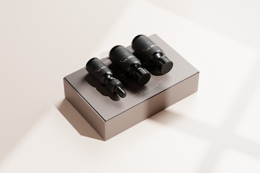 Three black dropper bottles are placed on a matte beige box with subtle shadows. The scene is minimalistic, featuring a neutral background with a soft lighting effect that creates a calm and luxurious appearance.