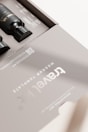 A sleek, modern packaging design featuring black bottles inside a matte gray box. The box is labeled 'Travel Kit' with clear, minimalistic typography. The design includes a QR code and some text detailing contents or instructions. The overall aesthetic is clean and sophisticated.