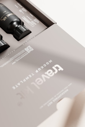 A sleek, modern packaging design featuring black bottles inside a matte gray box. The box is labeled 'Travel Kit' with clear, minimalistic typography. The design includes a QR code and some text detailing contents or instructions. The overall aesthetic is clean and sophisticated.