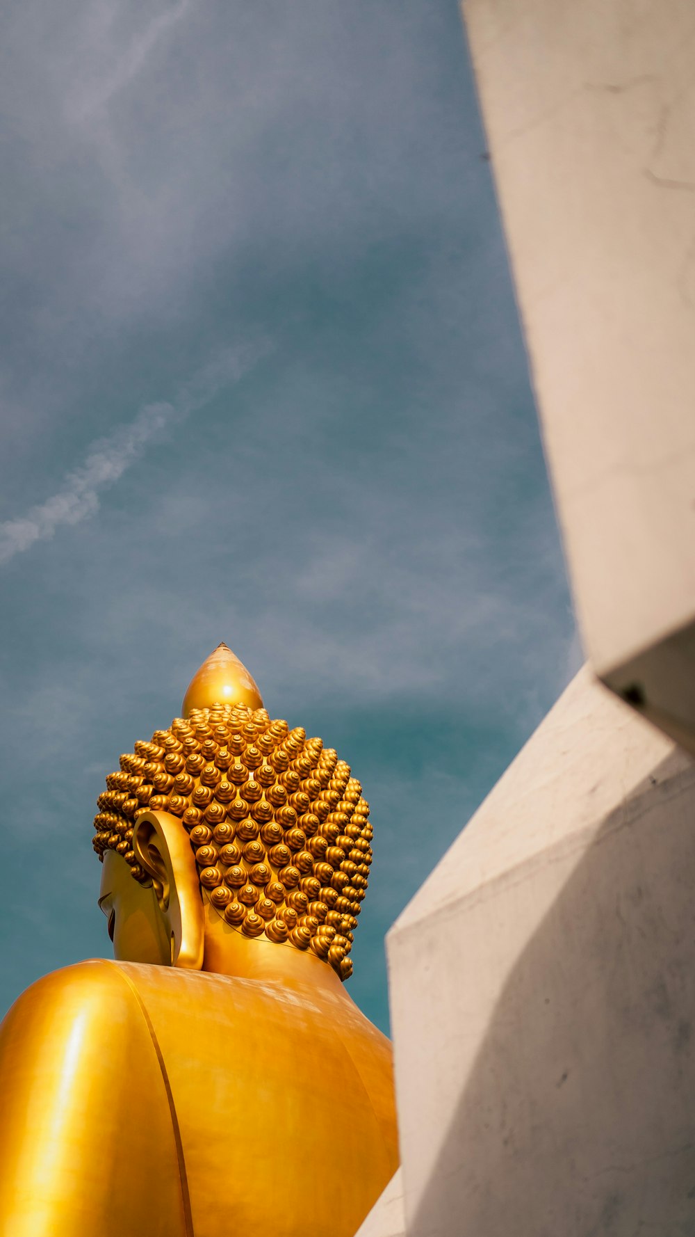 a golden buddha statue sitting in front of a blue sky
