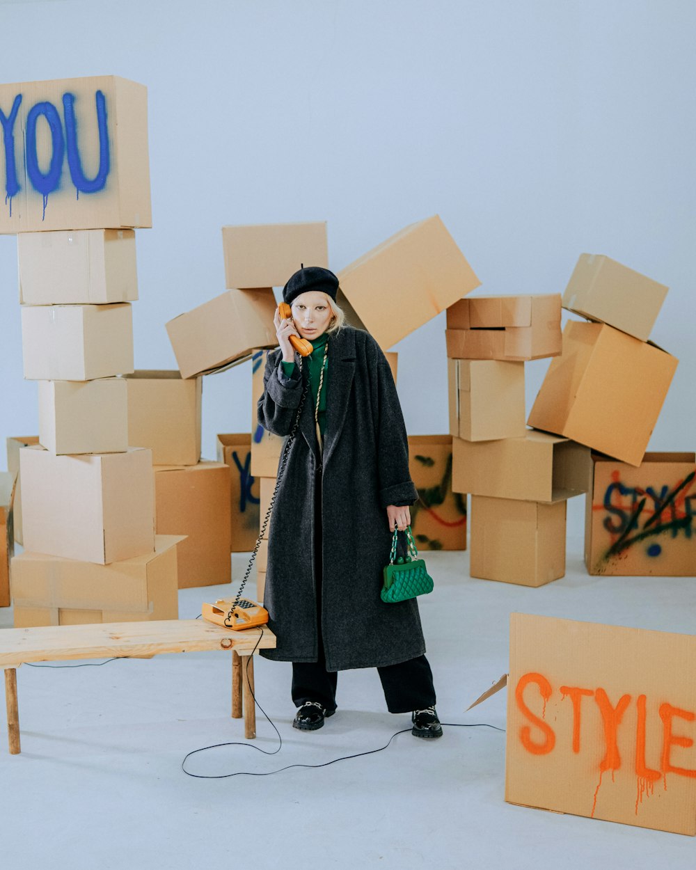a woman standing in front of cardboard boxes talking on a cell phone