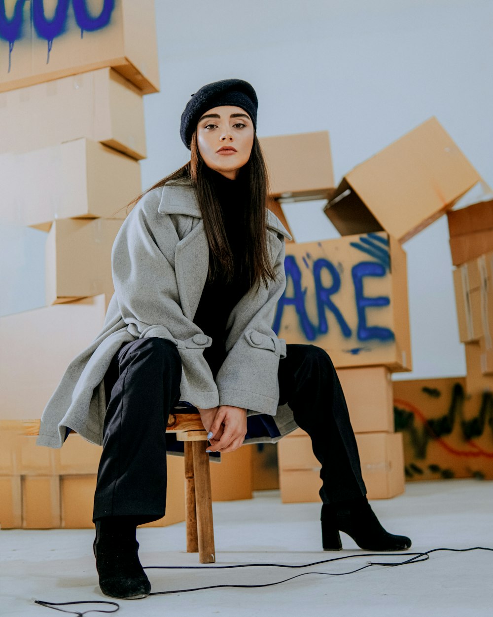 a woman sitting on a stool in front of boxes