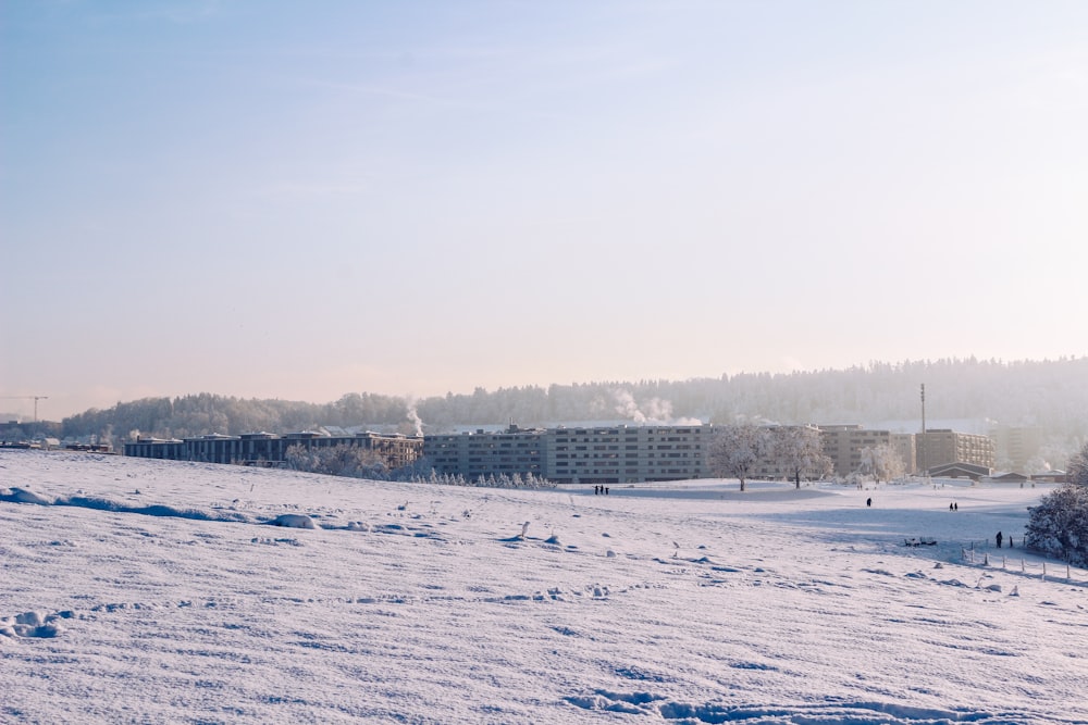 a snow covered field with buildings in the background