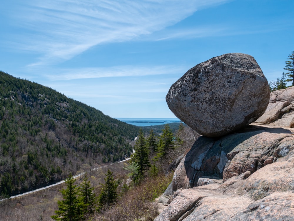 a large rock sitting on the side of a mountain