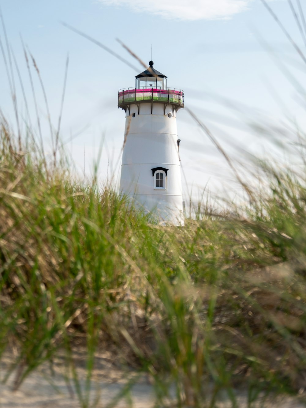 a white light house surrounded by tall grass