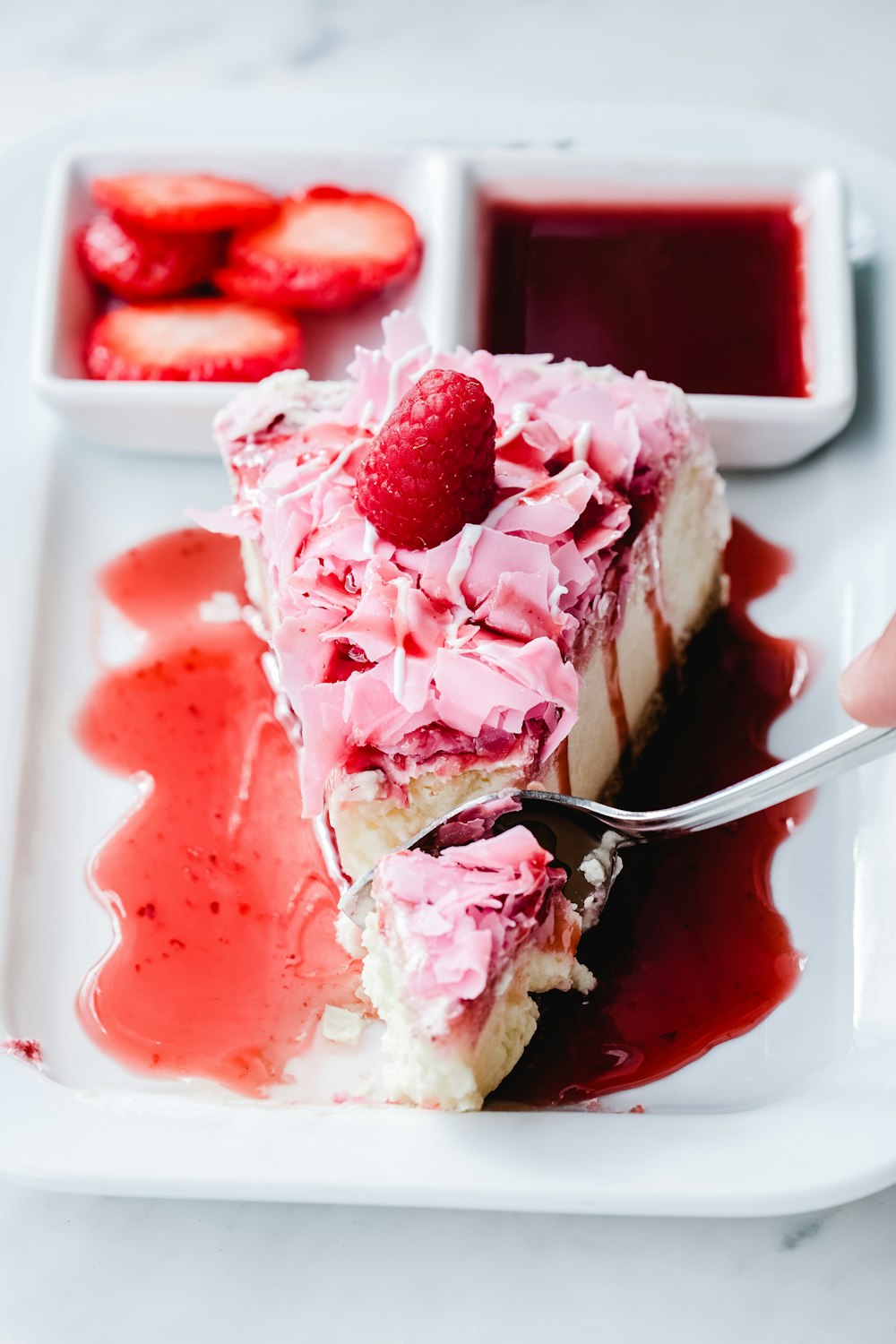 a white plate topped with a piece of cake covered in whipped cream and rasp