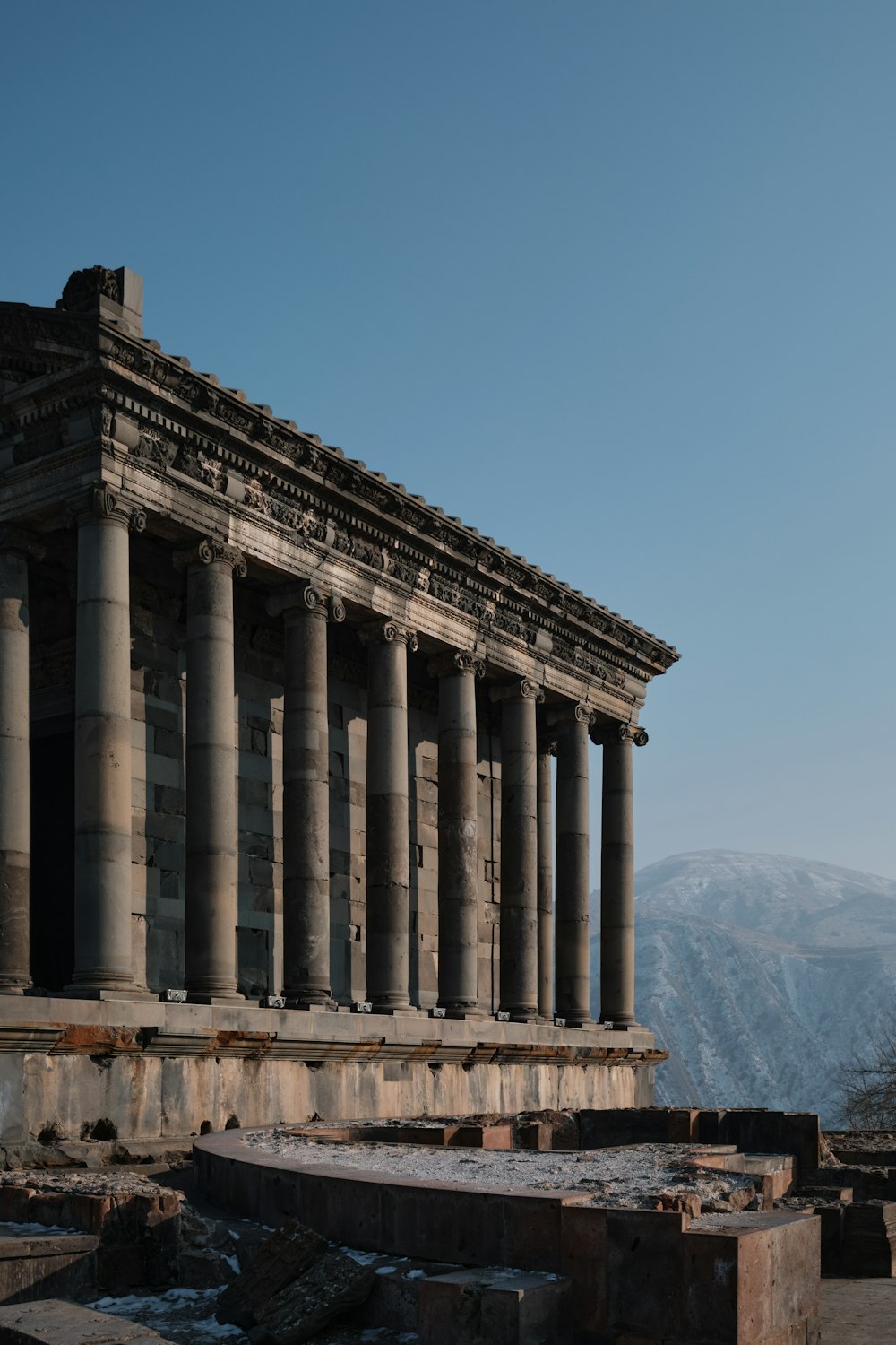Ein altes Gebäude mit vielen Säulen und einem Berg im Hintergrund