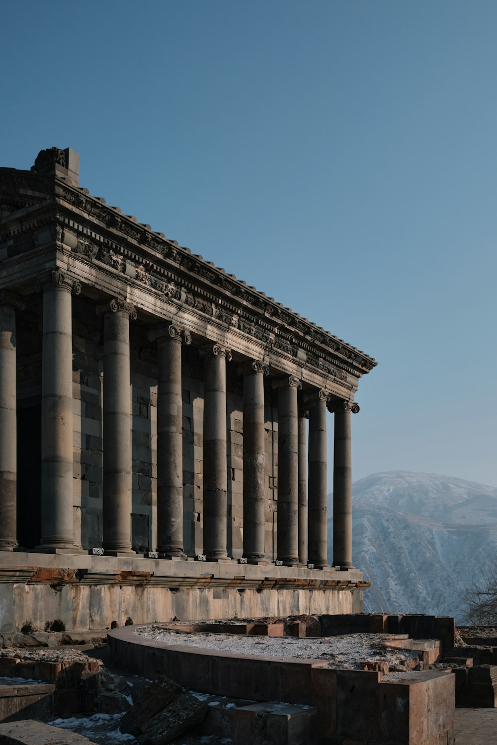 Un edificio antiguo con muchas columnas y una montaña al fondo